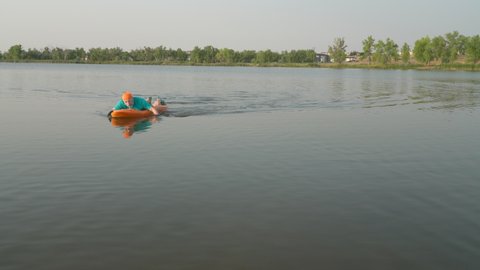 Fort Collins, CO, USA - August 5, 2021: Athletic, senior man is paddling Bellyak, a prone kayak, on a lake shore in Colorado, water recreation which combines the aspects of kayaking and swimming.