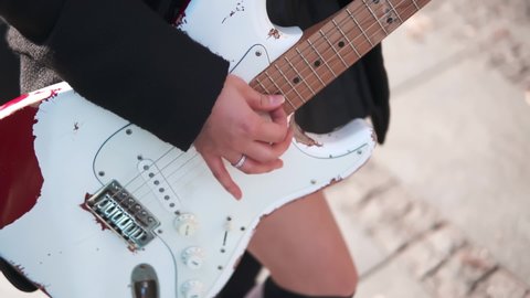 Close up of female hands playing vintage guitar. Asian girl like rock star performing show at the street. Music lifestyle