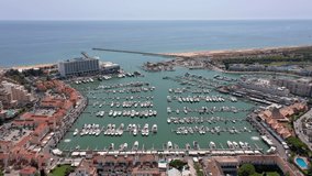 Aerial video of the tourist Portuguese town of Vilamoura, with views of the beaches and docks for luxury yachts, hotels and restaurants. Portugal, Algarve.