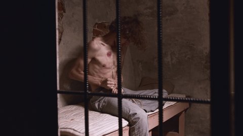 Horror acting - a shirtless man struggling in the prison cell wanting to commit suicide