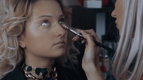 The young beautician applies the powder on the entire face area of the model, after which she tones the concealer under the eyes. The process of applying makeup at home by a professional. Artistic - Powered by Shutterstock - Get 15% off with code: PIKWIZARD15