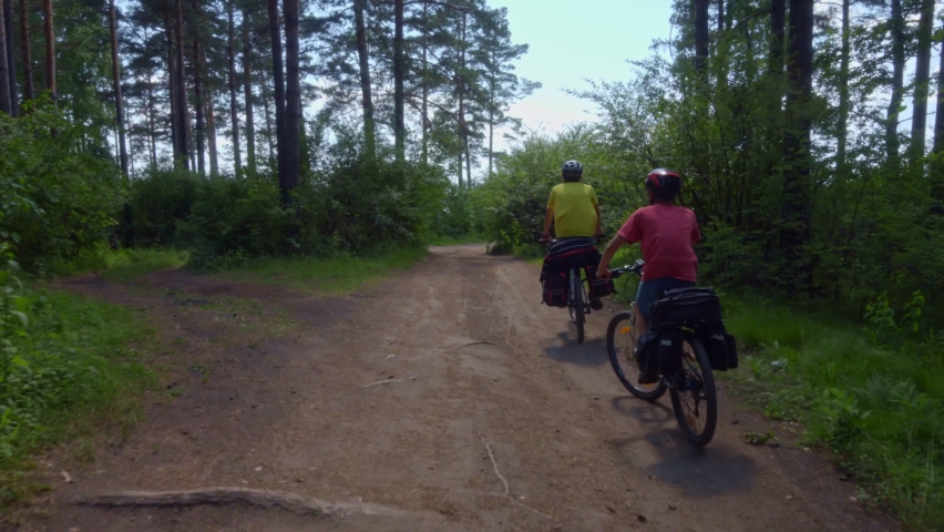 
Two cyclists drive out of the forest to the seashore.
Young bikers with backpacks ride bicycles along a picturesque road.