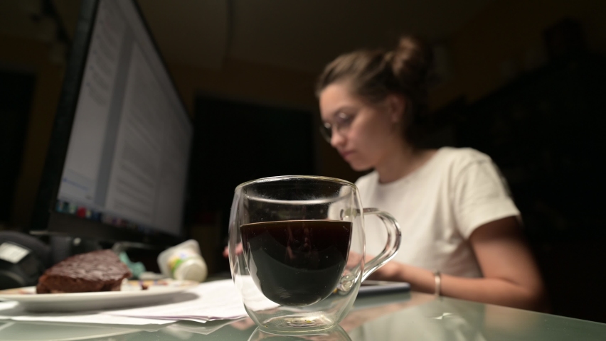 A young woman works at the computer at night and drinks coffee. Work at night Royalty-Free Stock Footage #1078313735