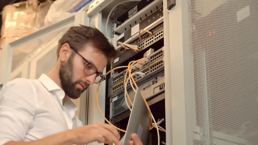 IT Technician Works With Ware And Cables In Big Data Center. Connecting Lan Cable To Mainframe.IT Engineer Patching Network Equipment In Server Room. Network Engineer Maintenance Work In Server Room Royalty-Free Stock Footage #1078317515