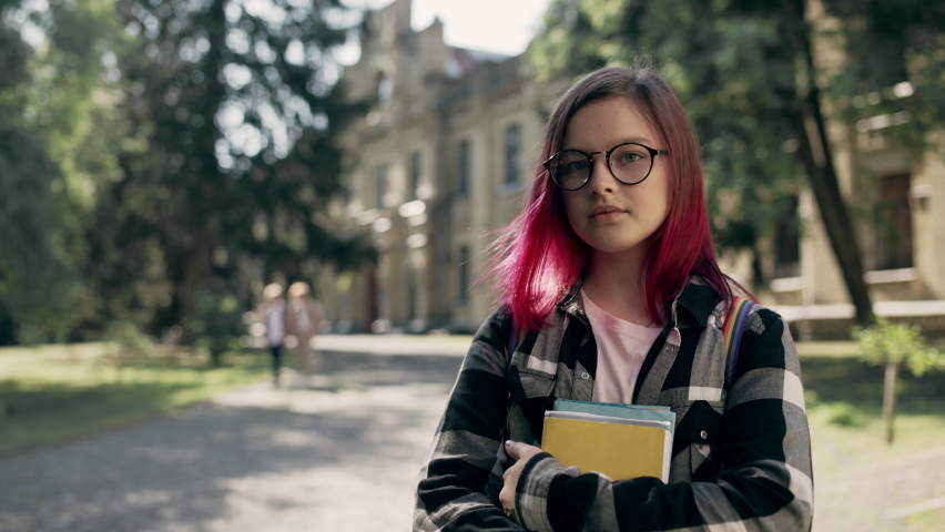 Serious hipster school girl adjusting eyeglasses, posing on camera with books Royalty-Free Stock Footage #1078320767