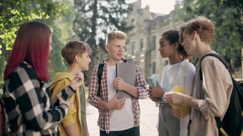 Multiracial middle school kids talking after classes, hanging out together