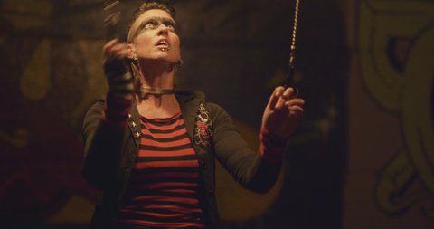 Steampunk female circus performer spinning fire poi at night