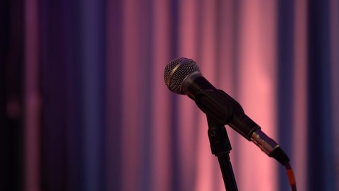 close-up of an isolated microphone on a stand in a club. Purple background. Performances. Oratorical skills.