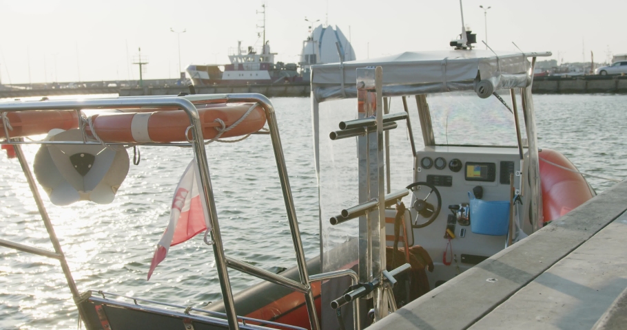 Poish bout in the port in a city od Hel in Poland, the boat is fitted with lifebuoys it is a motorboat parked. The Polish flag in waving in the wind. in the background we see port in Hel, Poland.