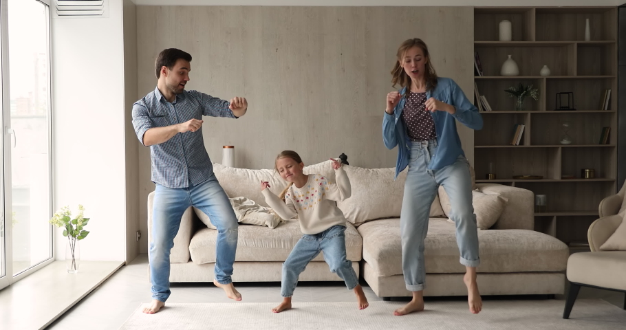Happy family with daughter dance barefoot in living room making funny Gangnam style movements feels overjoyed having fun together on weekend at home. Hobby, tenant, celebrate moving day to new house Royalty-Free Stock Footage #1078337885
