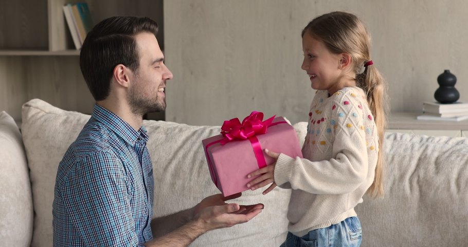 Loving daughter gives to daddy gift box congratulates him on birthday. Overjoyed man receive from caring kid present feels amazed, enjoy surprise, hug child express gratitude. Happy Father Day concept Royalty-Free Stock Footage #1078337945