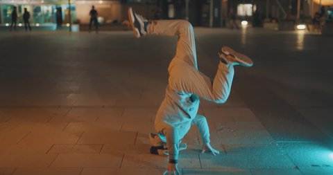 Young man breakdancing in urban street location at night