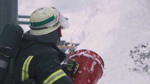 Anonymous fireman pouring white foam from hose while extinguishing fire during rescue operation
