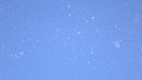SLOW MOTION, CLOSE UP, DOF: Scenic shot of the glittering diamond dust on sunny winter day. Tiny specks of diamond dust shimmer in the bright winter sunshine. Frozen snowflakes fall from the blue sky.
