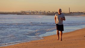 64 year old man getting his exercise at the beach at sunset. Slow Motion. - Powered by Shutterstock - Get 15% off with code: PIKWIZARD15