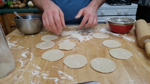 Home cooking - Adding few blueberries on round shaped thin pancakes or pies made from fresh dough and closing stuffing forming pierogi.