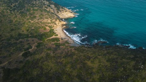 Idyllic Sardinia clear blue turquoise and calm water at a natural sand beach coast bay in Italy with sun and green forest. Aerial drone air flight at a tourist holiday destination on vacation island.