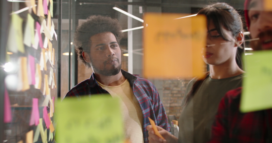 Creative hipster multiethnic team brainstorming near strategy board with colorful stickers. Young designers or developers coming up with ideas 4k footage Royalty-Free Stock Footage #1078352768