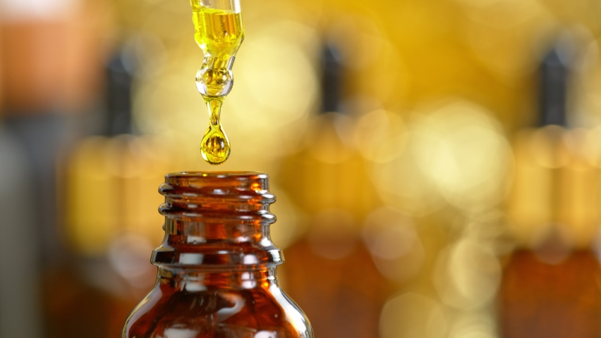 Super Slow Motion Shot of Oily Essence Drop into Phial on Golden Background at 1000fps.