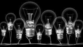 Shining light bulb with New Year 2022 and group of dark light bulbs in a row going from 2014 to 2021 isolated on black background. High quality 4k video.