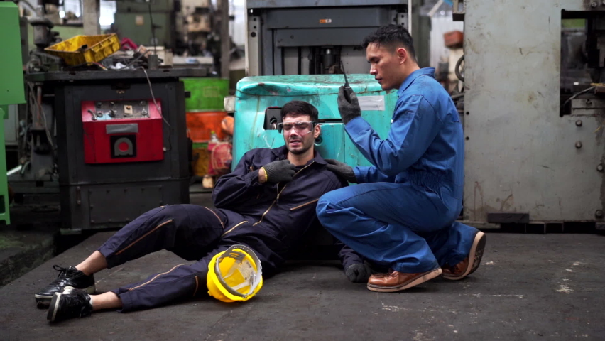 4K Man labor worker had accident unconscious on the floor at production line in metal factory. Male engineer supervisor talking on walkie talkie asking for help. Safety in industrial factory concept. | Shutterstock HD Video #1078371179