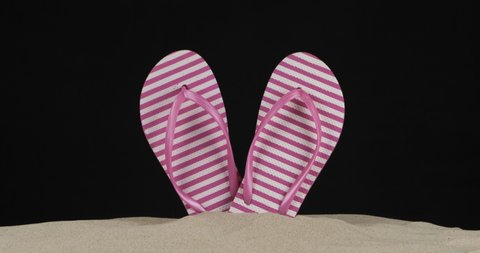 Panorama of beachside flip-flops sticking out of the sand. Isolated. Black background