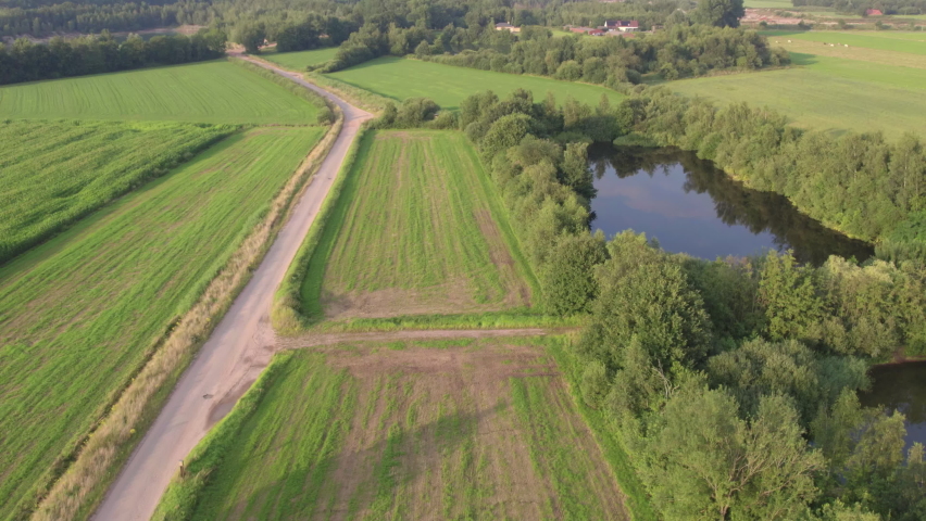 Drone flying over green meadows, a farm road and a pond, Kempen