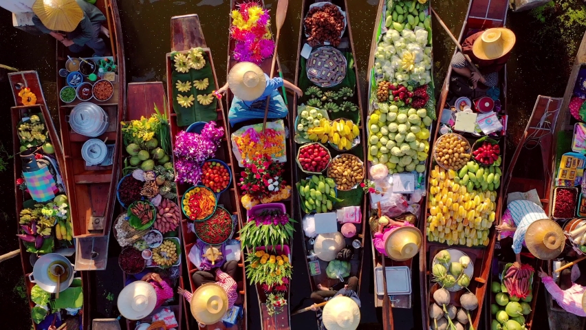 top view from drone of famous and unique floating market at Damnoen Saduak. Plenty of fresh fruits, vegetables, flowers and street food available to buy.  Royalty-Free Stock Footage #1078380857
