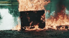 Retro vintage TV set against the background of river explodes beautifully with clouds of fire. Water is also burning. Concept of post apocalypse, surrealism and fire hazard of old worn out equipment - Powered by Shutterstock - Get 15% off with code: PIKWIZARD15
