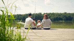 young happy family with little boy fishing a camping site. Parents with kids fishing together sitting on a wooden pier by pond spending weekend holiday outdoors. Back Rear view. catching the fish - Powered by Shutterstock - Get 15% off with code: PIKWIZARD15