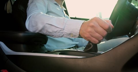 The driver of an electric car switches the lever of the car and takes the steering wheel with his hands, preparing the car for start