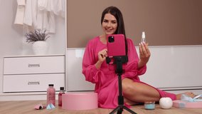 Blogger shoot unpacking cosmetics vlog on smartphone camera. Woman influencer, vlogger record video broadcast makeup on cellphone, cropped shot of young lady shopper sit hold delivered package