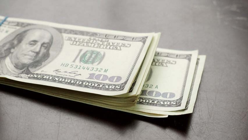 Hand counting pile of one hundred US banknotes over wooden table  in 4K VIDEO. Cash of hundred dollar bills, paper money currency.