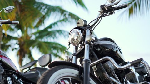 Dominican Republic, Santo Domingo - August 7, 2021: Close up of chrome plating chopper motorcycles parked under the palm tree. 