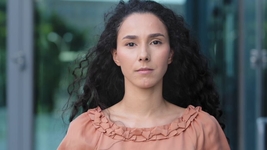 Female face close-up portrait outdoors hispanic young embarrassed puzzled girl brunette woman with curly hair with inquiring expression nods head yes answers positive agreement approval support agree | Shutterstock HD Video #1078401323