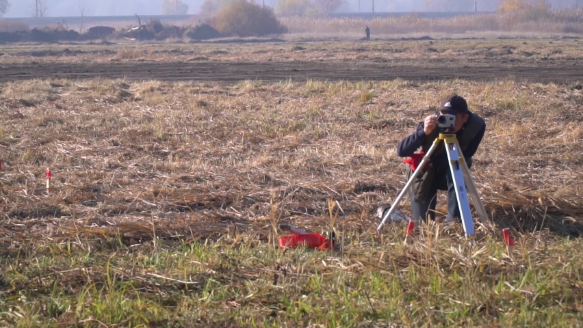 Geodesist is working in the field using a camera on a tripod