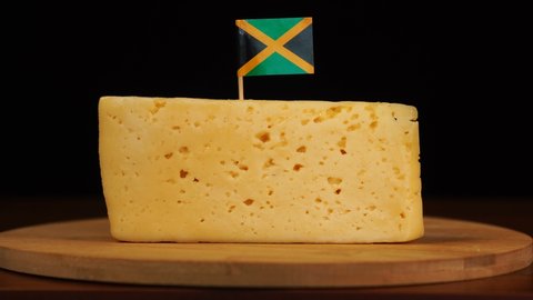 Man's hand put small in size toothpick with jamaican flag on cheese.