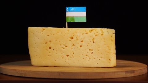 Man's hand put small in size toothpick with uzbek flag on cheese.