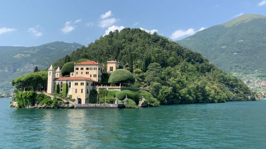 Landscape of Como Lake shore and Villa del Balbianello mansion house. This location is known as famous movies set.  Moving boat in Como lake. Tremezzina, Como Lake, Lombardy, Italy. Royalty-Free Stock Footage #1078417826