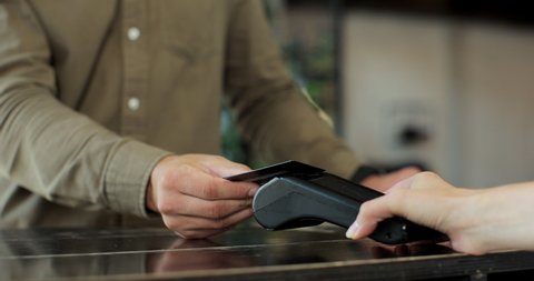 Close-up of unrecognizable caucasian man using credit card contactless payment for coffee wireless. Modern technologies and restaurant business concept.