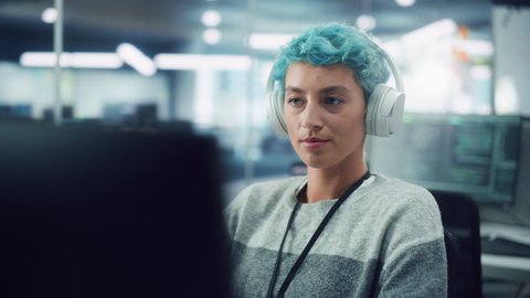 In Diverse Office: Portrait of Young Stylish Woman Working on Desktop Computer. Focused Motivated Girl Creating Modern Content, Colorful Project Design. Uses Headphones to Listen to Podcast, Music