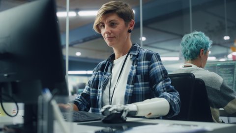 Diverse Body Positive Office: Portrait of Woman with Disability Using Prosthetic Arm to Work on Computer. Brave Professional with Futuristic Thought Controlled Body Powered Myoelectric Bionic Hand