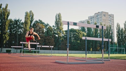 Low angle shot of a professional sportsman running a distance with obstacles. Young male athlete training in the stadium.