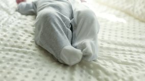 A newborn baby moves its legs, the baby's plump legs, close-up, lies on the mat, plays with its legs. Selective focus