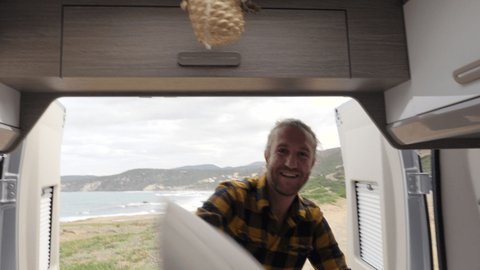 Point of view, couple having pillow fight in the back of a camper van. Alternative living, man in bed with sea views playing with pillow
