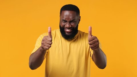 Confident leader young african american man 20s wear orange t-shirt point index finger camera on you motivating encourage show thumb up like gesture isolated on plain yellow background studio portrait