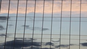 Timelapse video with sunset clouds reflection running. Modern building windows reflect color clouds 