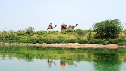 Pushkar, Rajasthan India August 19 2021: desert scene near water pond and far a camel cart safari going on sand, rajasthan tourism concept
