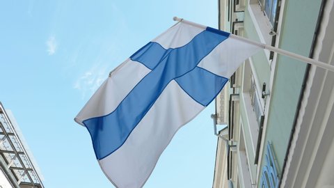 The Finland flag waving on the pole on the side of the building window in Estonia