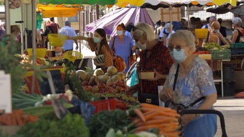 Aix-en-Provence, France - August 2021 : Women with face masks buying vegetables on the Aix en Provence market during the Covid-19 pandemic